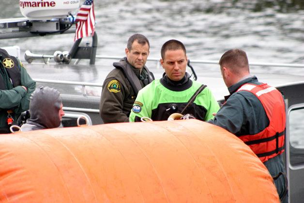 Divers from the Snohomish County Sheriff's Office get debriefed after retrieving the body of a 45-year-old woman from a submerged truck at the Mukilteo ferry dock.