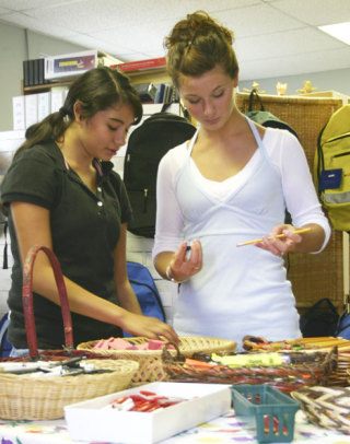 Volunteers Laura Hernandez and Anie Piehler look over items available to students at the Family Resource Center.