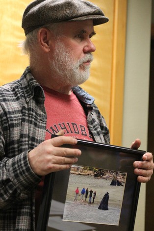 Fred Lundahl presents a framed photo of a gray whale spyhopping.