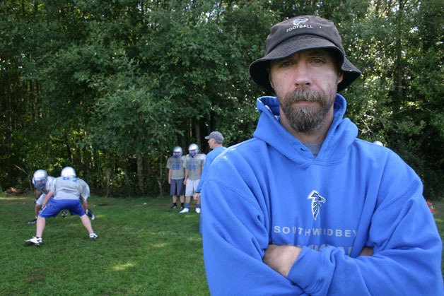 Leo Langer stands resolute as linemen practice behind him. The 42-year-old is in charge of the South Whidbey High School Falcon football team’s secondary