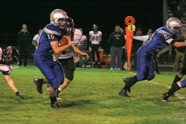 Falcon sophomore quarterback Nick French scrambles away from the Cedarcrest pass rusher as he gets some help from Mason Shoudy blocking up front.