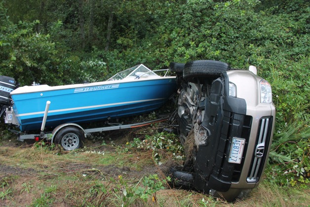 A Honda Pilot SUV rests on its driver's side after tumbling down the ditch on Bush Point Road on Friday afternoon. The driver and passenger were both unharmed.