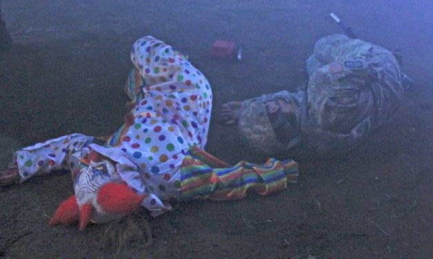 A psychotic-zombie-clown lays next to a fallen military-style escort at the zombie apocalypse course set up at Island Greens in Clinton. The Halloween-time attraction runs from 7 to 11 p.m. Thursday.