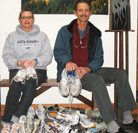 Kelly Henriot and Blake Willeford and their personal stash of running shoes. The two have organized a charity drive on South Whidbey starting Jan. 25 to collect gently used sneakers and sandals for distribution in Africa.