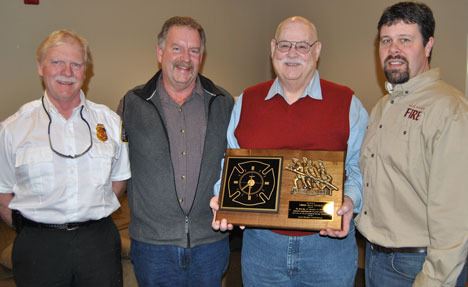 Fire District 3 Chief Dan Stout poses with a plaque presented at his retirement gathering in Freeland recently. With him are new chief H.L. “Rusty” Palmer and District 3 commissioners Mike Helland and Kenon Simmons.