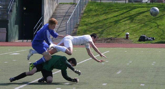 Sam Turpin collides with Mariner senior mid Elliott Noell and senior goalie Drew Ronson during the first half of the match Saturday.