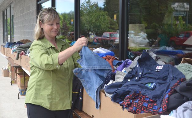 Rita Burns folds jean shorts at Ken’s Korner during the Good Cheer-organized sidewalk sale over the weekend. This was the first year for the sidewalk sale