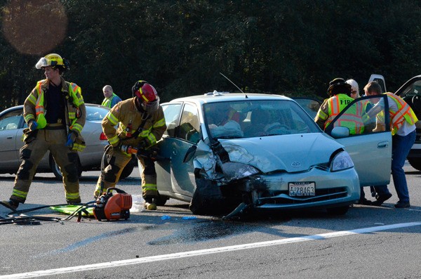 South Whidbey Fire/EMS firefighters work to free an accident victim from a crash on Highway 525 in Freeland Monday.