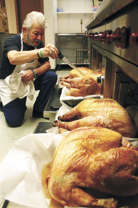 Volunteer cook Dan Saul bastes a line of waiting turkeys earlier this week as the Mobile Turkey Unit prepares food for this year’s free feast.