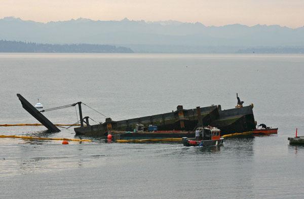 Workers attend to a barge that partially sank Wednesday