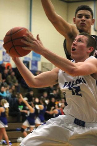 Falcon junior Parker Collins spins under the hoop to evade Wildcat freshman Abe Lucas on Tuesday