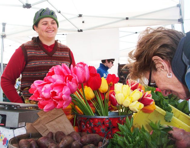 Anna Peterson waits as a customer sniffs out her favorite flower scent at Molly’s Island Garden booth at the Bayview Farmers Market