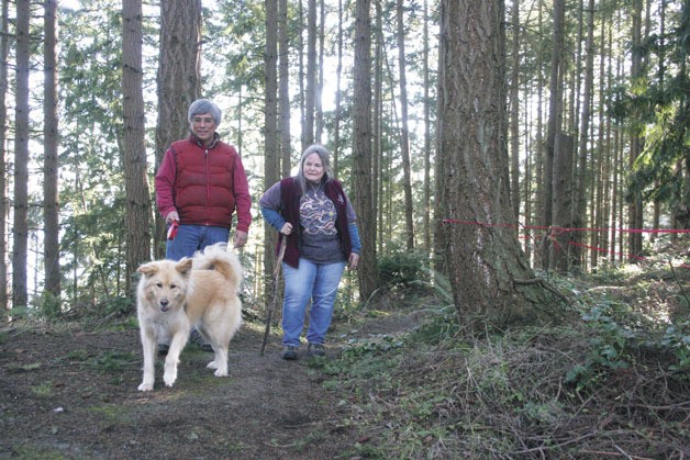 Clyde and Marcia Monma and their dog Galina reach the top of the Dorothy Cleveland Trail. Red tape stretched around trees to the right shows the location for a turnaround for a proposed cell phone tower.