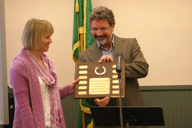 Valerie Brown receives the Extra Mile Award plaque during last week’s school board meeting from South Whidbey Schools Foundation vice president Chris Gibson.