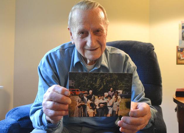 Harold Robinett holds up a photo showing three generations of his family. In the photo are his parents