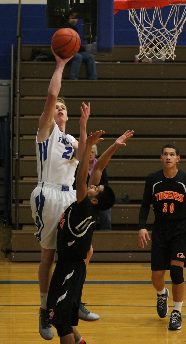 Falcon senior Chandler Sutton leaps over Granite Falls senior Ezra Chavez in the first quarter of Tuesday’s boys basketball game at South Whidbey High School.