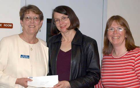 Good Cheer executive director Kathy McLaughlin accepts a check for $500 from Gail Pierce of Coldwell Banker Tara Properties while Good Cheer’s Shawn Nowlin looks on.