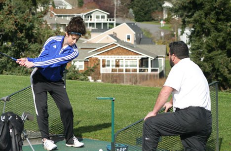 Falcon girls golf coach Tom Sage offers a few seasoned pointers to junior Myca Christensen at Useless Bay Country Club's driving range on Tuesday.