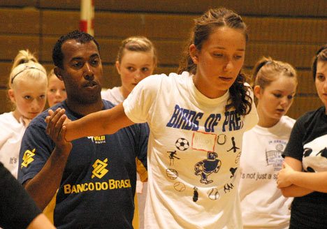 Volleyball clinic trainer Gylton Da Matta shows Allison Wood and fellow clinic athletes the best way to stretch the body after a tough workout Wednesday at South Whidbey High School.