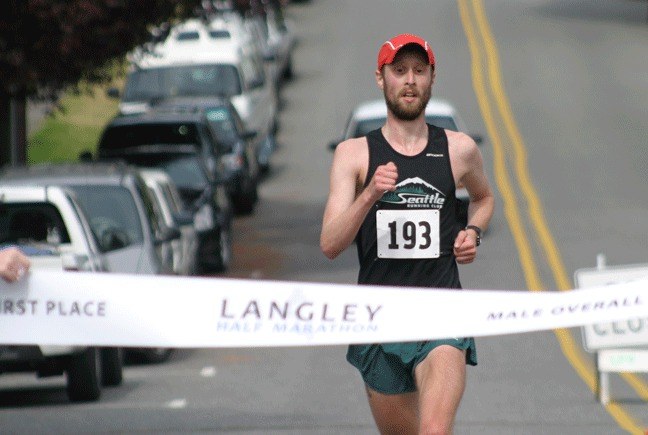 Maxwell Ferguson breaks the “finish line” banner for first place. The 25-year-old runner finished in 1 hour