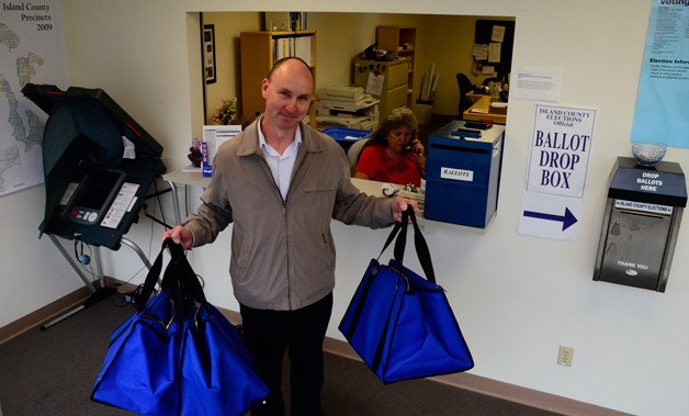 Elections Office administrator Kirk Huffer hefts bags used to transport ballots from collection boxes.