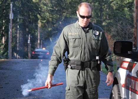 Island County Sheriff's Deputy Dan Todd gets ready to place a flare on Lakeside Drive at Goss Lake after a tree fell onto the roadway