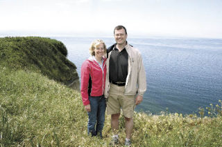 Bruce and Melissa Russell stand at the rim of their 150-foot bluff overlooking West Beach near Coupeville. They are the 500th household in Island County to become Shore Stewards.