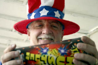 Kiwanis chairman Dave Jones admires a “TNT Rustler” as he helps stock the shelves Thursday at the Kiwanis fireworks stand at Ken’s Korner.