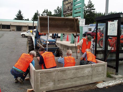 Friends of Freeland volunteers place one of 24 new planter boxes in a downtown Freeland parking lot. From left are local sculptor Sue Taves