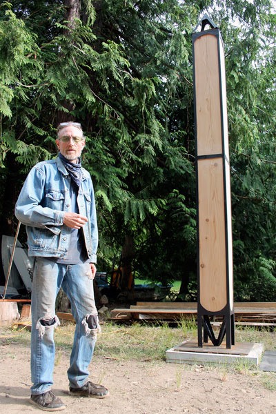 Dexter Lewis stands beside his sculpture “Piercing the veil of deception” at his outdoor carving studio. The piece will be installed in front of the post office in Langley.