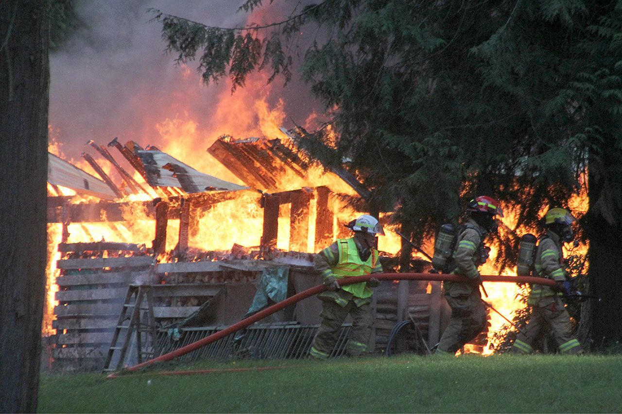 Kyle Jensen / The Record Firefighters lug a firehose around to fight the fire from a different angle.