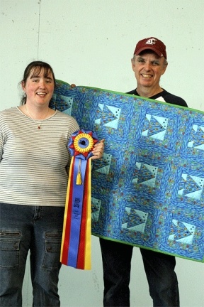 Molly Kay holds up the ribbon that will be awarded to the winner of Island County Fair's Super 17 Challenge while her father