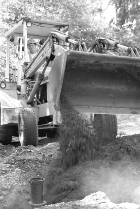 Garth Batchelor of J & D Wallace Construction backfills around a water main that will be used to connect a new well to the Freeland Water District's storage tank on Scenic Road.