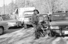 State troopers investigate one of the damaged Island County Sheriff’s patrol cars that was involved in bringing to an end the slow-speed chase of the pickup truck in the background that was pulling a trailer. The chase went north from Oak Harbor over the Deception Pass Bridge and was concluded on a rural road in Skagit County.