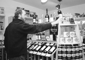 Wine Shop Manager Randy Turner displays one of the 58 varieties of local wine available at the Greenbank Farm's Wine Shop. Farm managers are pleased with how well the shop is doing financially.