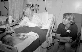 Clancy cuddles with Annabel Smith while Joy Thompson spends time with Smith at Whidbey General Hospital. Thompson wears a green Delta Society shirt that matches Clancy's vest. They are true partners -- both of their pictures are on the photo ID cards Thompson wears.