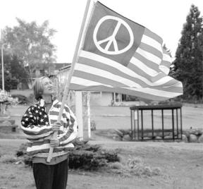 Janis Schurr displays the peace flag she used to protest the Iraq war Saturday in Coupeville. A passing motorist apparently first believed it was an American flag and wrestled it away from her.