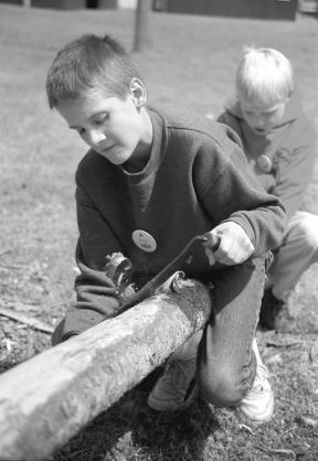 Fifth-grader Josh Parsons works enthusiastically to scrape the bark off a log Wednesday during Living History -- Pioneer Days at the fairgrounds.