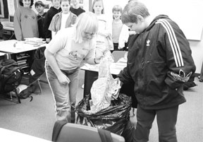 Students Greg Nelson and Cherese Taggart dive into teacher Maribeth Crowe’s garbage bag to pull out packaging that can be recycled.