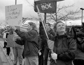 Victoria Rice looks up at the flag during an Oak Harbor rally to support U.S. troops in the Middle East. She helped put together Wednesday afternoon's rally the previous night after watching TV news