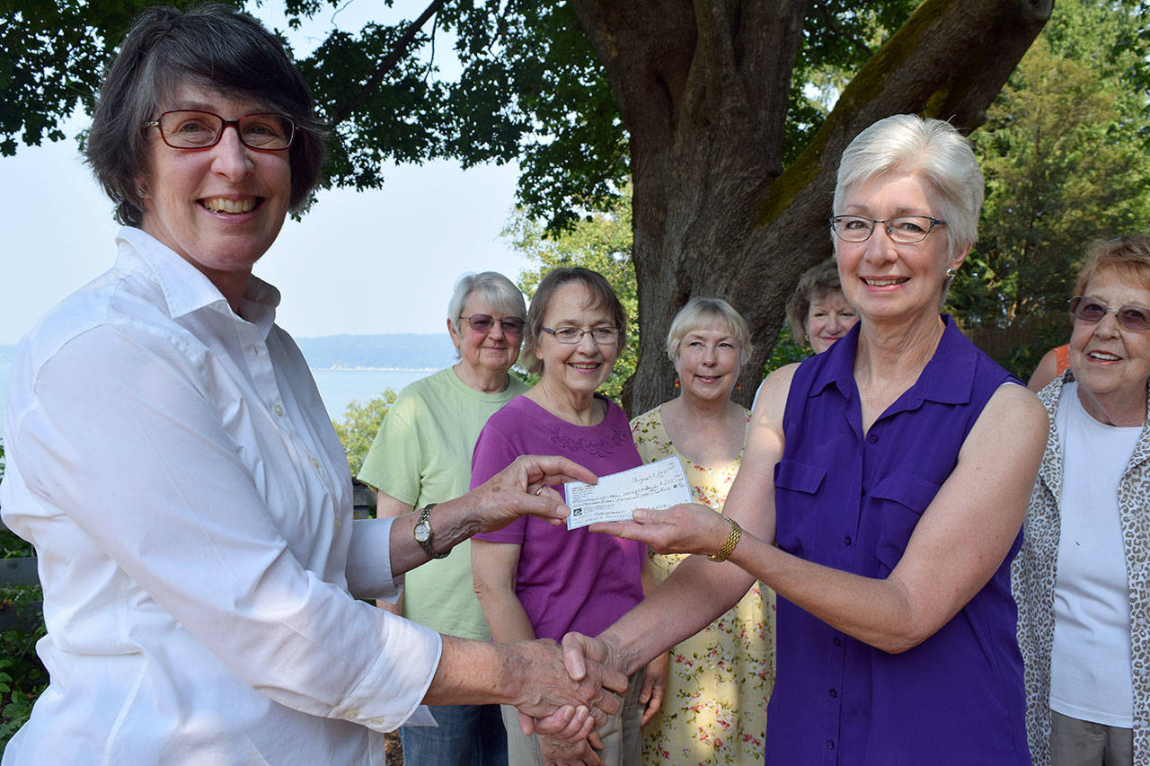 Kyle Jensen / The Record — Janice O’Mahony, left, presents League of Women Voters Co-President Carla Grau-Egerton, right, with a check for $2,100 as League members look on.