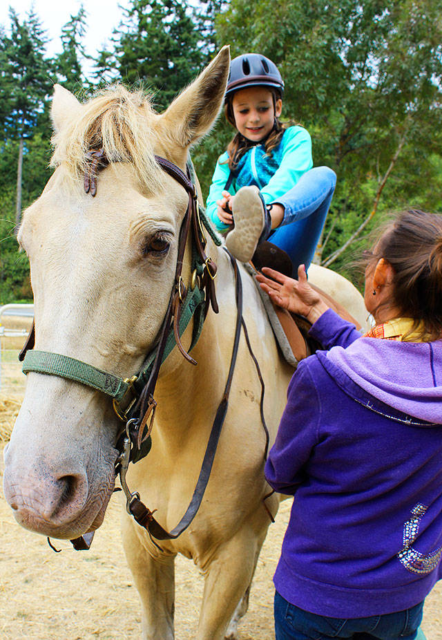 Aida Daly saddles up on Tango with instructions from Sue Landusky, owner of Stride ‘N Glide. Daly was treated to a birthday trail ride with her family by her grandmother. Photo by Patricia Guthrie/Whidbey News-Times