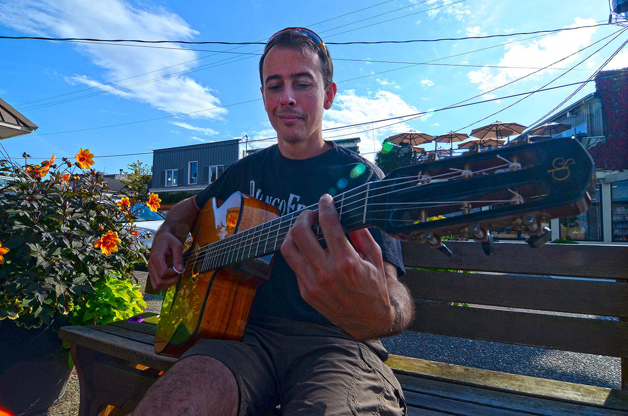 Record file — A DjangoFest Northwest participant strums an impromptu tune in downtown Langley during the 2013 festival.