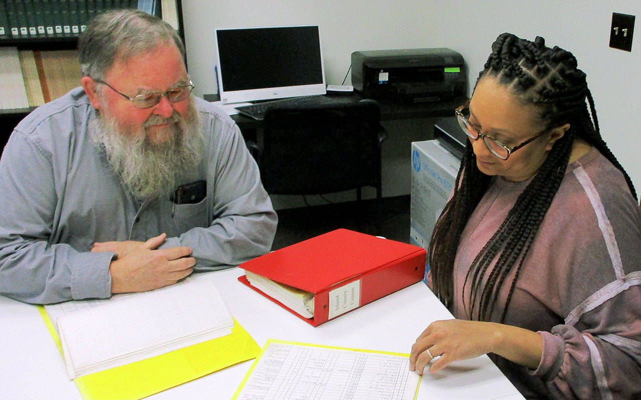 Photo by Dave Felice                                At the Island County Historical Museum’s Langley Archive Research Center, genealogy researcher Guy Calkins of Freeland and Museum Archivist Cassie Rittierodt discuss Whidbey Island census records. The museum keeps a notebook containing transcribed entries of all island census records from 1850 to the present day.