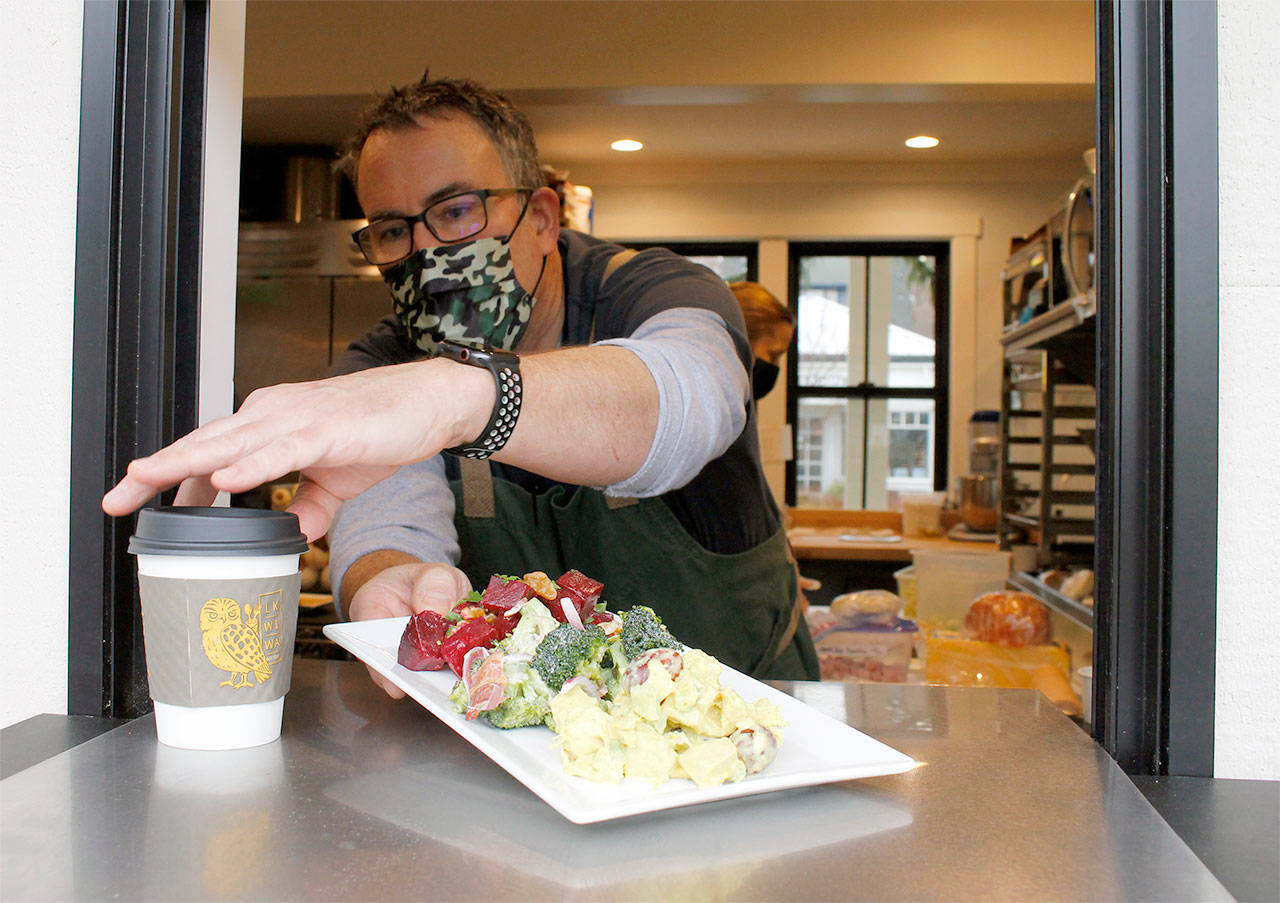 Jim Goodall arranges some food in the to-go window, where customers pick up their food from outside at Langley Kitchen. Photo by Kira Erickson/Whidbey News-Times