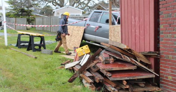 Construction workers repair damage done by a truck that crashed into the wooden building adjacent to Penn Cove Pottery. As of Monday afternoon, the truck had not been removed due to structural integrity concerns at the site of the accident. (Photo by Karina Andrew/Whidbey News-Times)