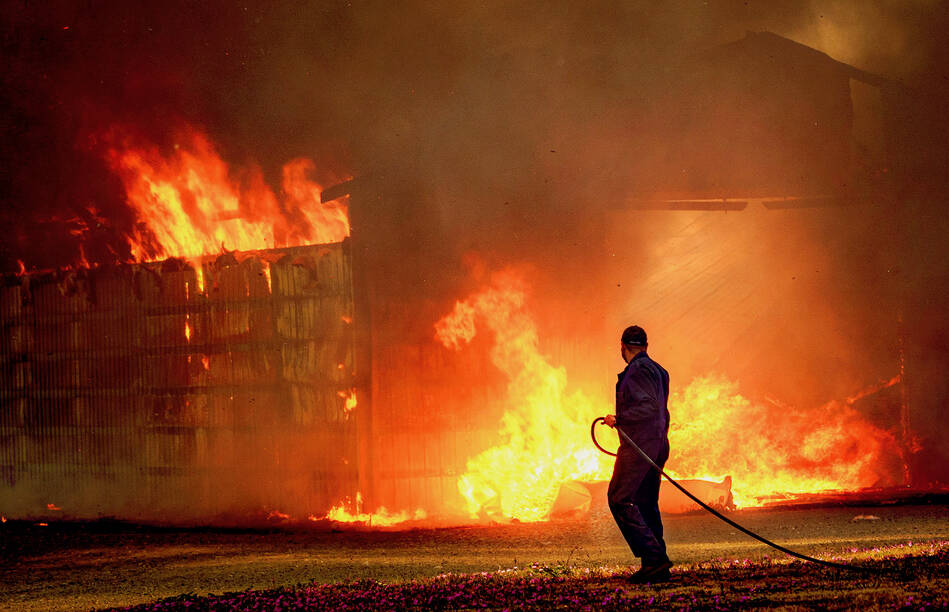 Samuel Romo, an employee of Island Potato, tries to help stop the fire from spreading with a garden hose. (Photo by David Welton)