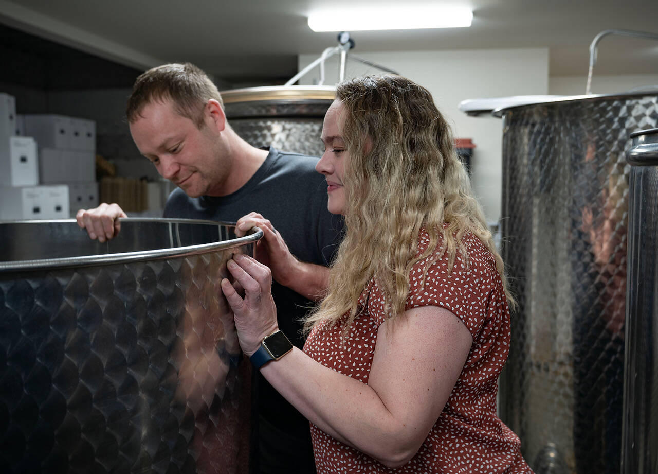 Kyle O’Neill and Michelle Graham peer into a tank of wine. (Photo by David Welton)