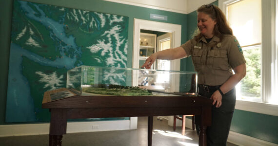 Interpretive specialist Jen Gray interacts with a Fort Casey map in the new Admiralty Head Lighthouse exhibit. (Photo by Sam Fletcher)