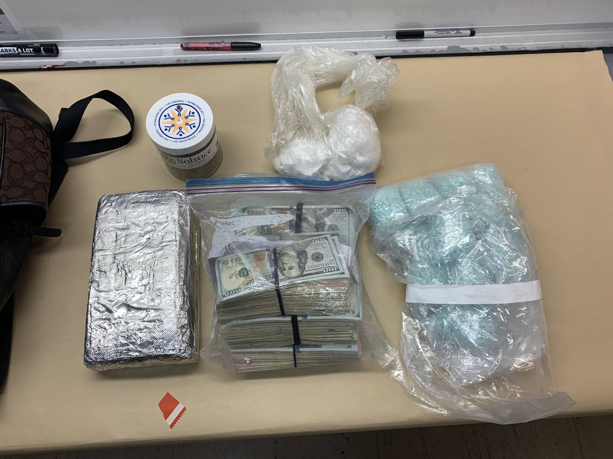An Oak Harbor police photo shows plastic bags of suspected cocaine, a foil-covered brick of suspected cocaine, $79,000 in cash and large number blue “M30” pills.